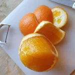 Eine Orange, von der die Schale großzügig abgeschnitten wurde, sodass keine weiße Haut auf der Orange zurückbleibt.